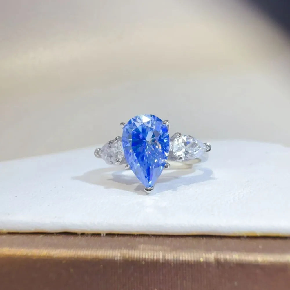 Elegant 2 carat moissanite teardrop ring featuring a stunning blue center stone and sparkling side stones