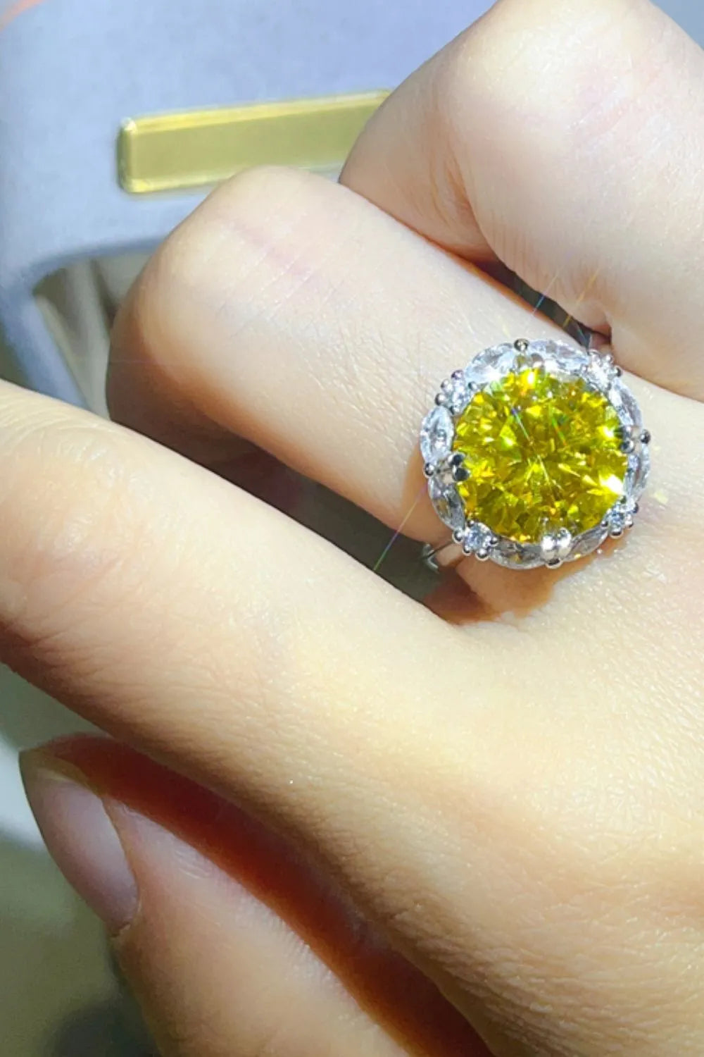 5 carat moissanite ring with a vibrant yellow stone and sparkling halo setting on a hand