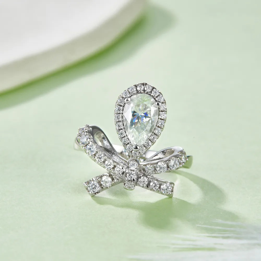 Elegant affordable moissanite rings featuring a pear-shaped stone and a bow design, perfect for special occasions