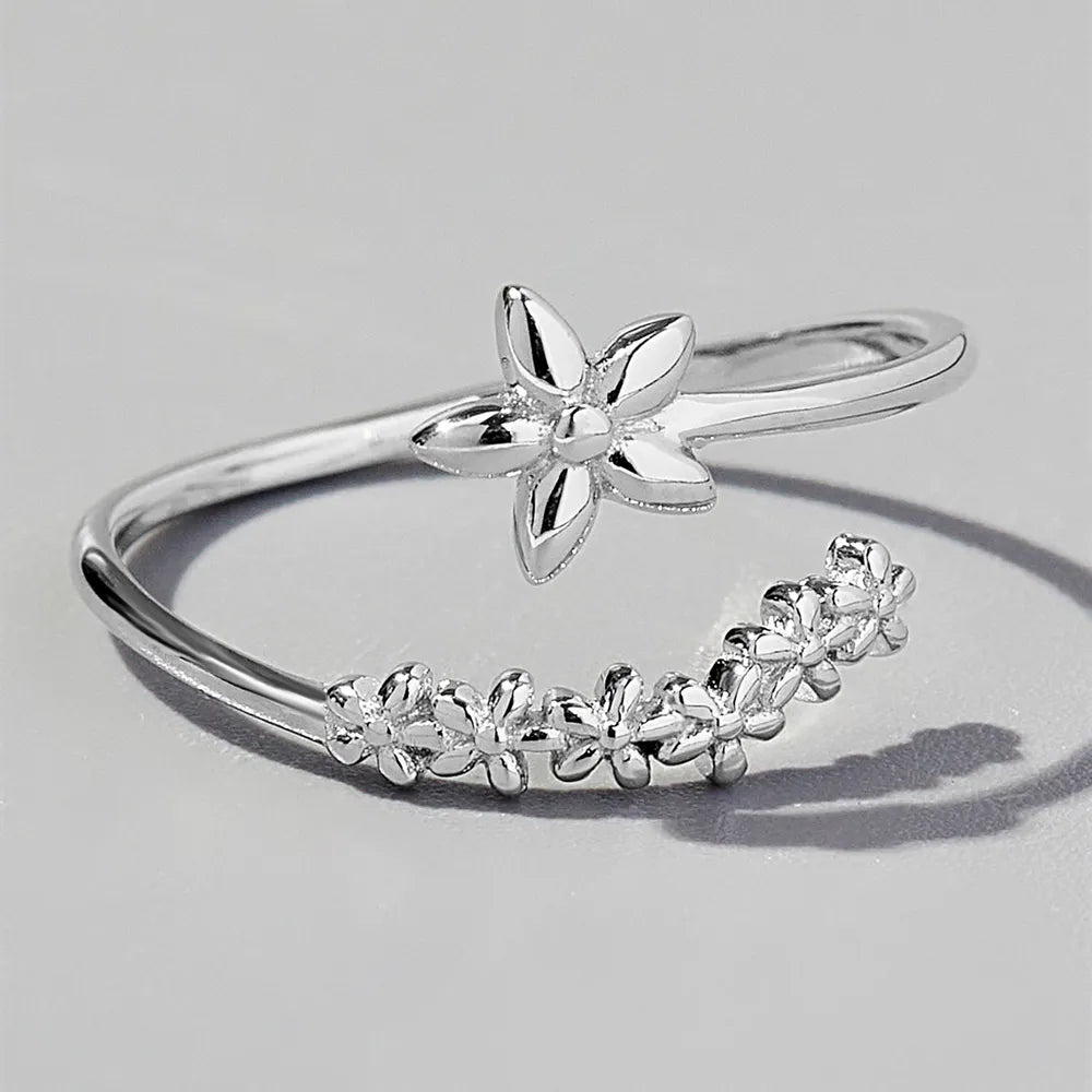 Delicate floral silver ring featuring a blooming flower design and a curved band