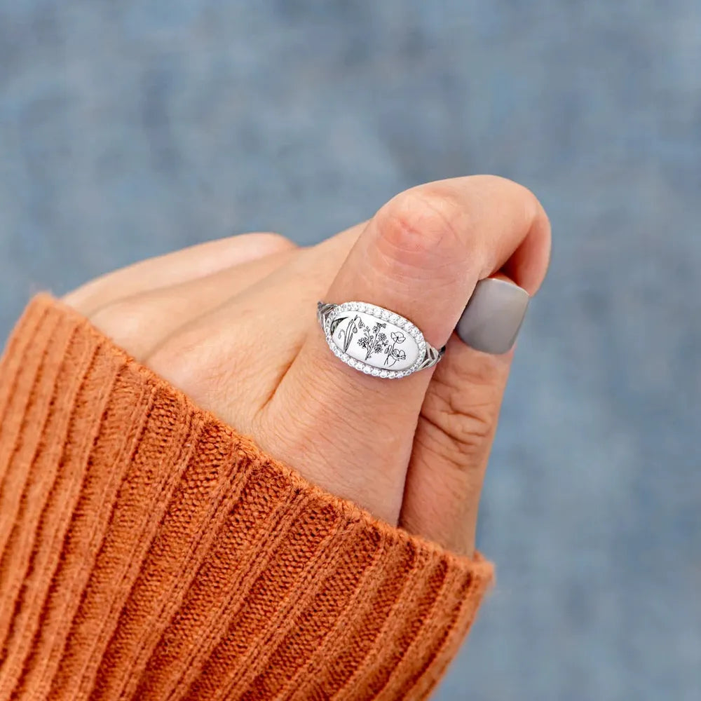 Handcrafted gemstone flower ring displayed on a fingertip with a cozy sweater background