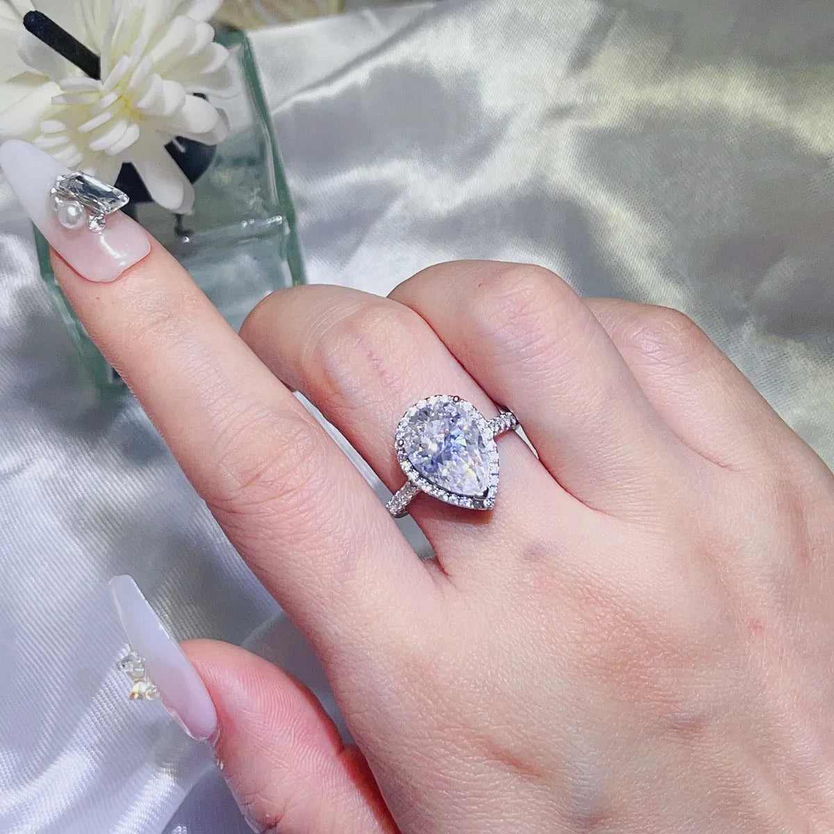 Elegant pear shaped moissanite ring on a hand, showcasing its sparkle and prong setting