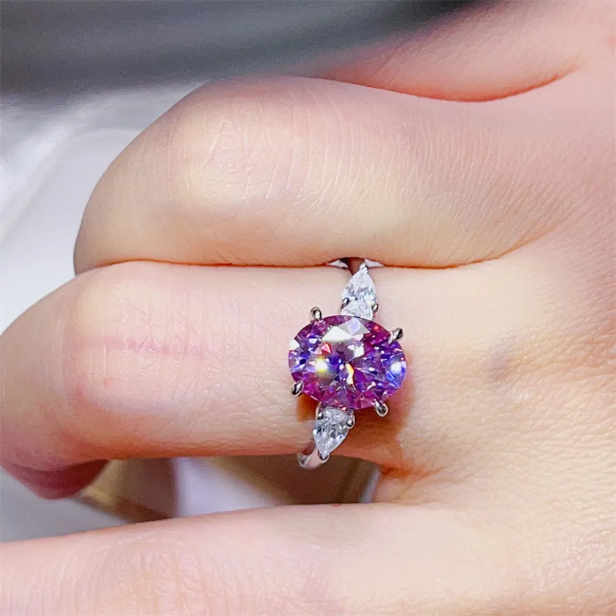 Stunning purple moissanite bridal jewelry ring with oval cut and side stones on a hand