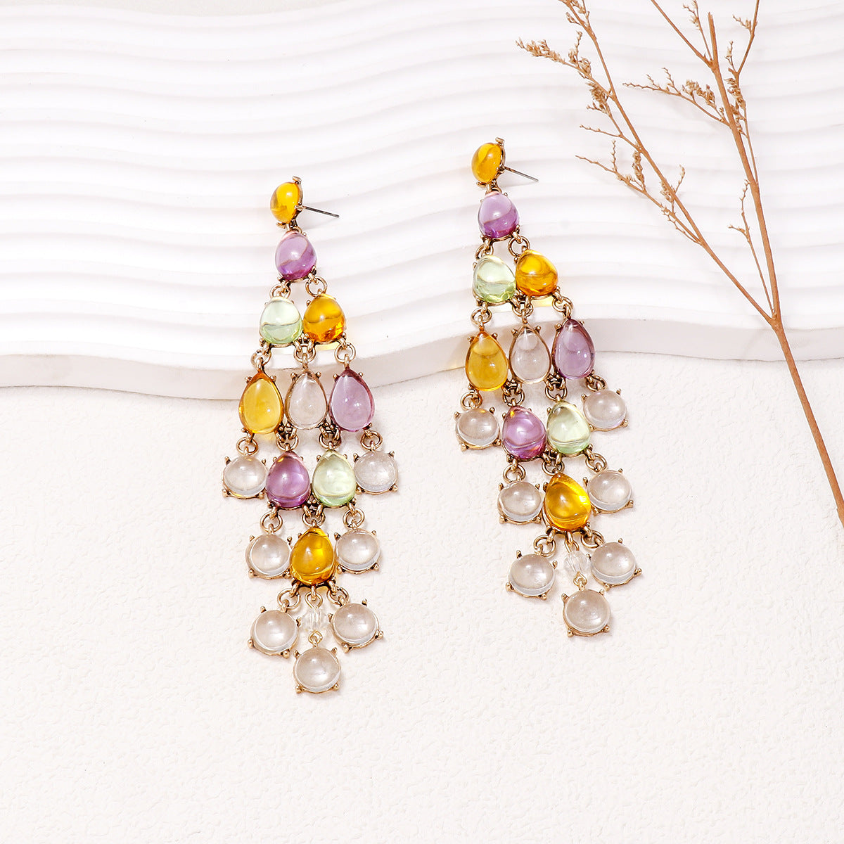 Colorful chandelier earrings featuring red teardrop earrings with vibrant yellow and purple accents
