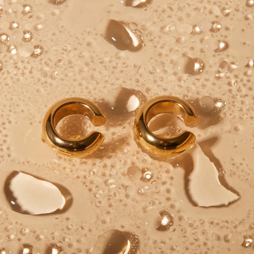 Gold Clip On Earrings for Women Sitting on a Wet Surface with Water Drops