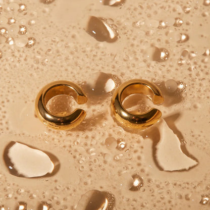 Gold Clip On Earrings for Women Sitting on a Wet Surface with Water Drops
