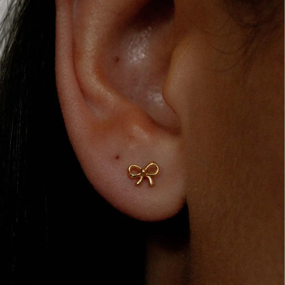 Copper bow stud earrings displayed on a model's ear for stylish everyday wear