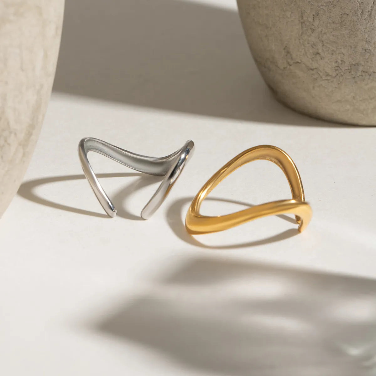 Gold and silver ring set displayed on a neutral background with textured vases