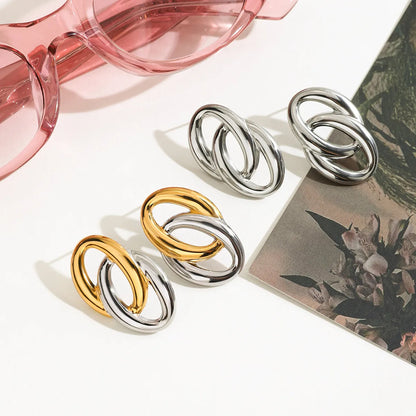 Trendy modern twist hoop earrings in silver and gold displayed with pink sunglasses